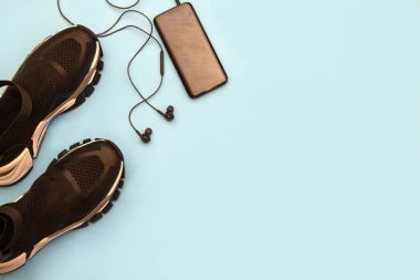 Spor seti, Fitness aksesuarları düz mavi arka planda yatıyordu. Moda Ayakkabı, kulaklık, vücut egzersiz, üst görünüm için telefon. Aktif yaşam konsepti.