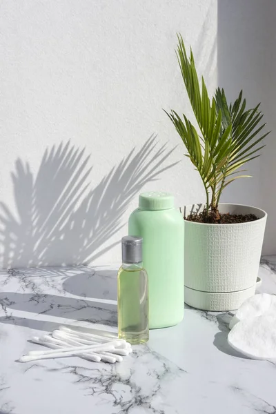 Cosmetic skincare products on marble background with palm leaves shadow. Glass bottle of natural oil, modern concept of organic beauty trend skin care