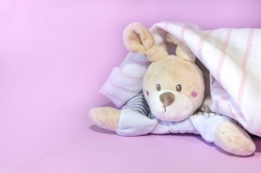 Komik yenidoğan bebek oyuncakları, pembe arka plan üzerinde duş sonra havlu altından dışarı gözetleme oyuncak tavşan. Kopyalama alanı, düz döşeme, üst görünüm.
