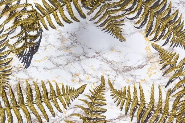 Golden fern leafs, palm frond on marble background. Trendy creative design