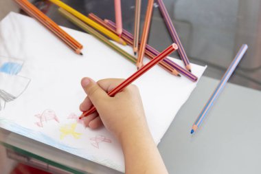 Çocuk renkli kalemler le çizer. Japon balığı, araba ile balıkçılık teması çocuk çizim