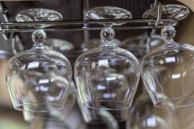 Temiz boş konyak bardakları sırayla hafif güneş ışığında raf çubuğuna asmak