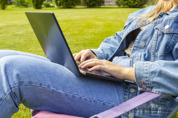 Parkta çimüzerinde dizüstü bilgisayar kullanan kadın, açık havada net kitap üzerinde çalışan öğrenci öğrenci
