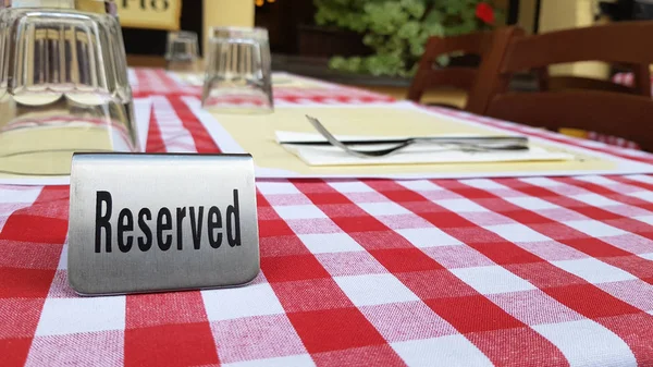 Reserved table in outdoor cafe, metal tag on table restaurant reservation.