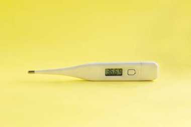 Açık sarı arka plan üzerinde 36,6 sıcaklık ile dijital tıbbi termometre.