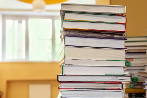 Stack of books on table in school library on blurry background. Concept back to school. Close-up, copy space