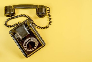 Vintage siyah telefon ile bir kulaklık ve sarı zemin üzerine sarmal tel kablo