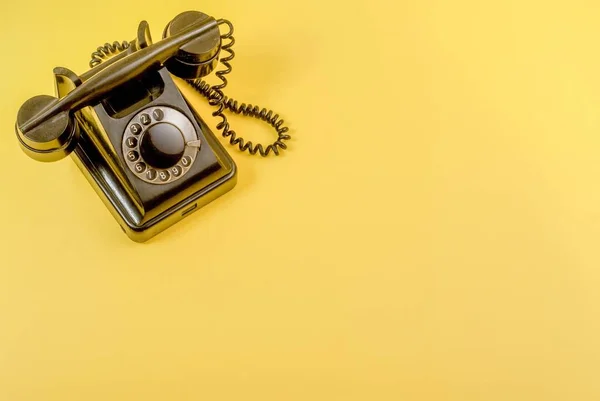 Vintage siyah telefon ile bir kulaklık ve sarı zemin üzerine sarmal tel kablo