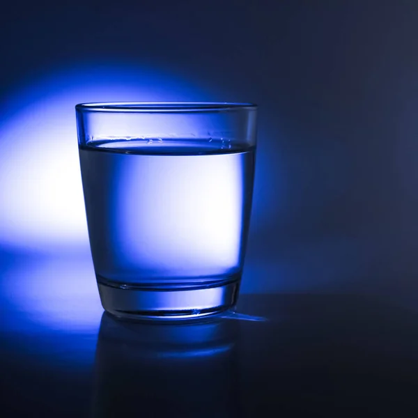 Glass of water with abstract blue light reflections