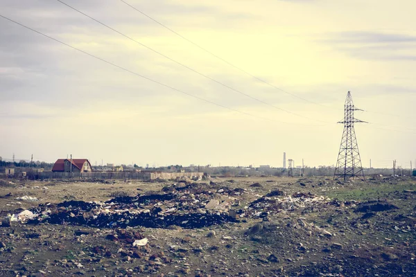 Electricity poles and a house on a dirty and polluted wasteland.