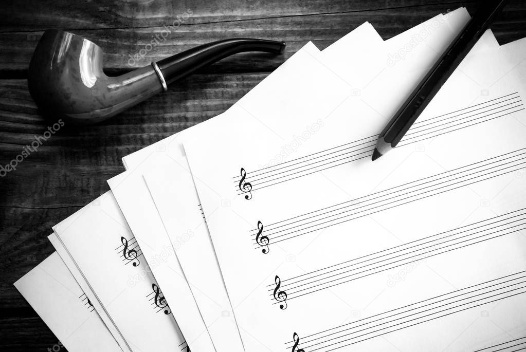 Empty music score pages and a smoking pipe in black and white. Stave pages and a pipe.