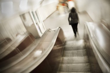 Metrodaki yürüyen merdivendeki genç bir bayanın bulanık görüntüsü. Merdiveni bulanıklaştırıyor.
