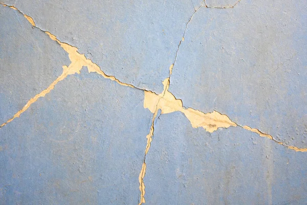 Peeling paint on the wall. Crack on the wall. Wall with cracks on a blue paint.