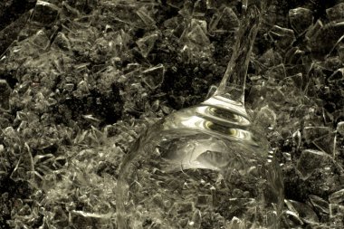 Kırık cam arka planla birleştirilmiş boş bir şampanya kadehi. Alçak bir tonda cam kırıkları üzerinde şarap kadehi..