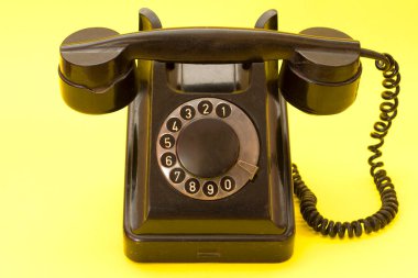 Sarı arka planda antika bir telefon. Kablolu eski sabit hat telefonu..