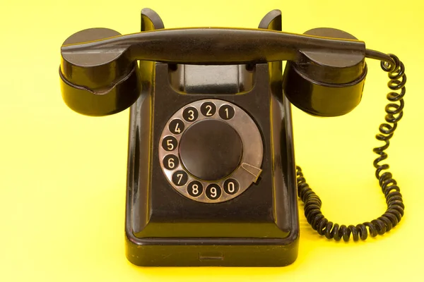Sarı arka planda antika bir telefon. Kablolu eski sabit hat telefonu..