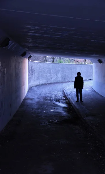 一个黑暗的人站在黑暗的隧道里 免版税图库照片