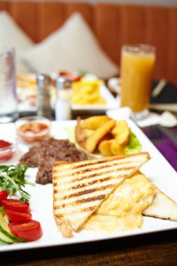 Kahvaltı yemek - omlet yumurta, patates ve salata ile biftek ile sandviç - görüntü. Bulanık arka plan