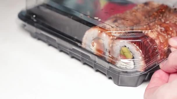 Woman opens a plastic container with fresh Japanese sushi. — Stock Video