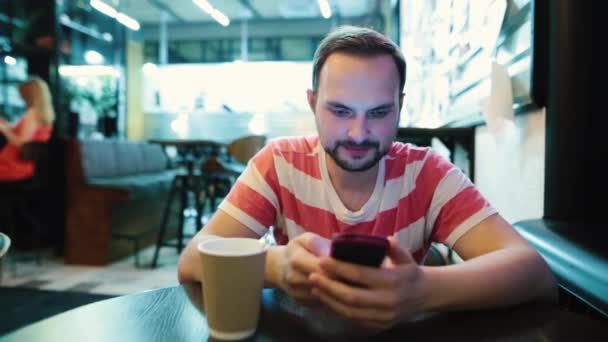 Young bebaarde man gebruik mobiele telefoon in café. — Stockvideo