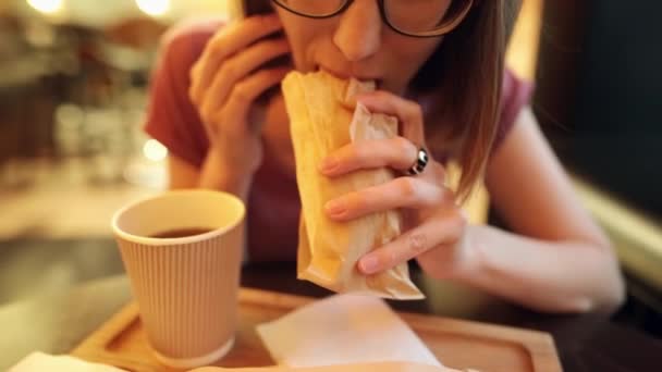 Hipster girl mange un délicieux donateur de poulet juteux avec un thé, s'amuser .