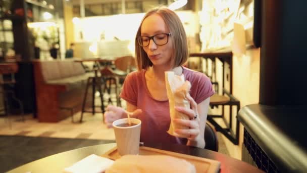 Hungriga leende kvinna äter en läcker kyckling shawarma eller doner. — Stockvideo