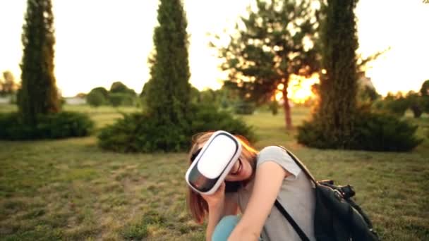 Femme utilise des lunettes de réalité virtuelle dans la forêt. Lumière du coucher du soleil, fusées éclairantes, heure dorée. Relax, concept nature et technologie — Video