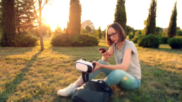 Caucásico chica en gafas de chat utiliza el teléfono inteligente. El sol de la noche brilla . — Vídeo de stock