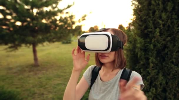La mujer utiliza unas gafas de realidad virtual en el jardín. Hora de la tarde dulce . — Vídeos de Stock