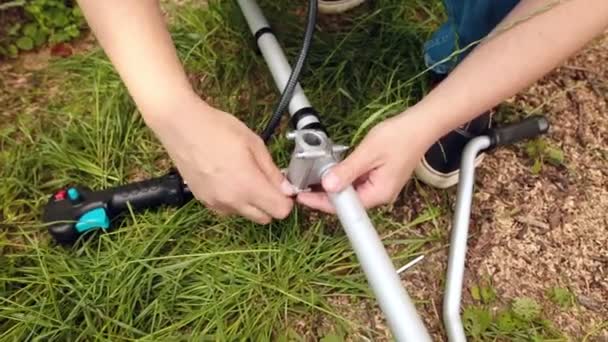 Um homem montando cortador de arbustos ou cortador de cordas no jardim . — Vídeo de Stock