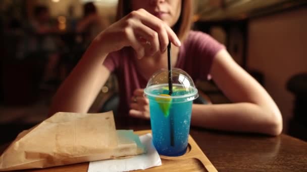 Κοντινό πλάνο του όμορφη γυναίκα πίνοντας λεμονάδα πάγος γαλάζιο στο καφενείο. — Αρχείο Βίντεο