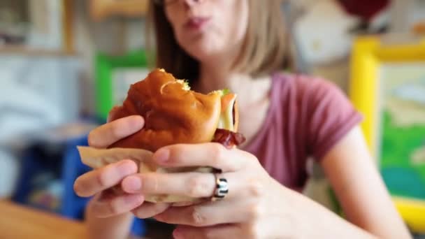 Zblízka hlad dívka se těší čerstvé hamburger. — Stock video