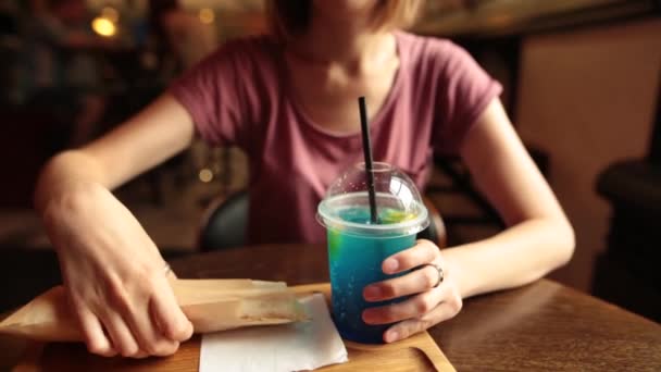 Hipster-Frau trinkt eisblaue Limonade und Hühnchen-Döner im Café. — Stockvideo