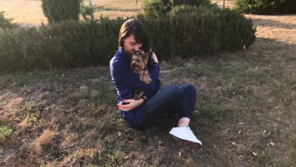Joven morena abrazando y besando a su perro Yorkshire Terrier . — Vídeos de Stock