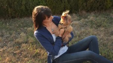 Sevimli kız ve sevimli köpek Yorkshire terrier açık havada günbatımında sonbahar parkta oturan.