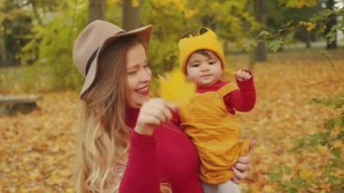 Mutlu Interracial aile. Rahat anne ve karışık yarış bebeği sonbahar parkta eğleniyor.