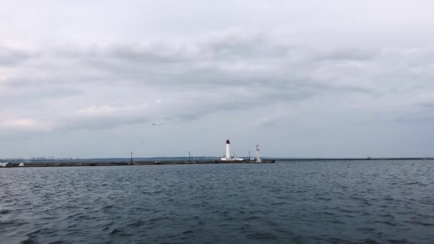 Sirályok repülnek át a magányos világítótorony. Felhős időjárás. Tengeri kikötő, Odessa, Ukrajna. Fekete-tenger. — Stock videók