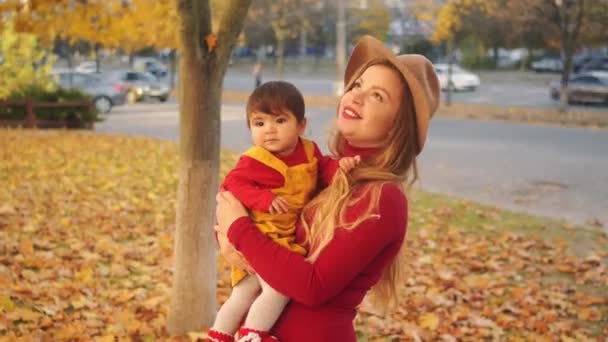 Gelukkig jonge moeder speelt met haar kleine gemengd ras babymeisje. Warme zonnige herfstdag. — Stockvideo