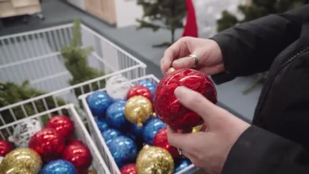 Meisje houdt een Nieuwjaar speeltje in haar handen - rode bal. Kopen van nieuwe speelgoed voor Kerstmis. — Stockvideo