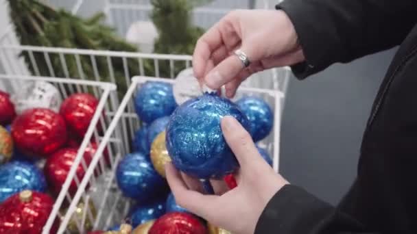 Vrouw kiest Christmas speelgoed, heeft in haar handen blauwe en gouden ballen. — Stockvideo