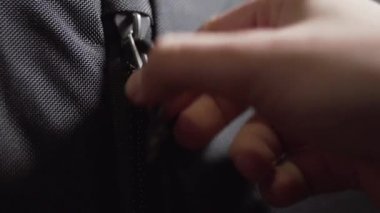 Adam unzips ve siyah spor sırt çantası fermuarlar.