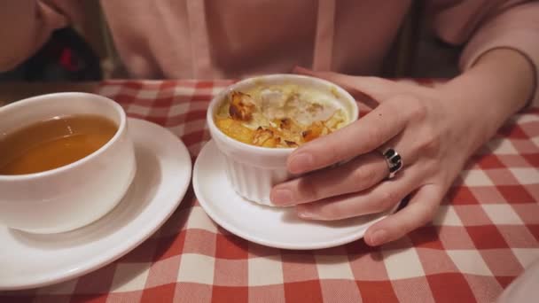 Frau isst Pudding mit Apfel, Kürbis und Orangenschale, trinkt Tee in einem Café. — Stockvideo