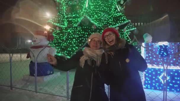 Felice madre e figlia con scintille sono in piedi vicino all'albero di Capodanno e divertirsi . — Video Stock