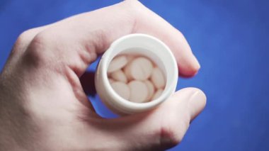 Erkek el yavaş yavaş bir kavanoz içinde hap gösterir.