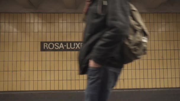 BERLIN, ALLEMAGNE - 22 NOV 2018 : Un homme marche devant la caméra sur fond de l'inscription de la station de métro Rosa Luxemburg Platz . — Video