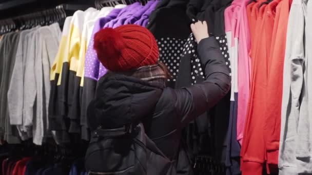 Donna che sceglie vestiti di moda nel negozio al dettaglio nel centro commerciale della città. Concetto shopping . — Video Stock