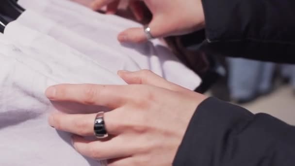 Girl chooses fashionable t-shirt. Close-up shot of a female hands. — Stock Video