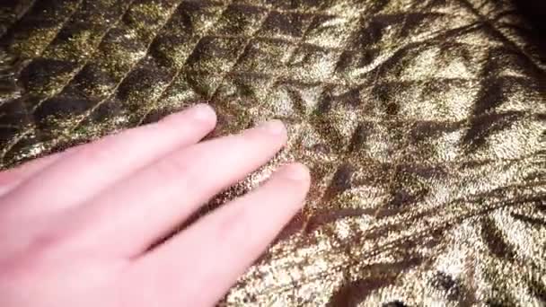 Male hand slides over smooth synthetic golden nylon and polyester fabric. — Stock Video