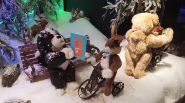Münih, Almanya - 20 Kasım 2018: Mekanik oyuncak tavşan direksiyon simidi bir bisiklet üzerinde döner. Yanındaki iki oyuncak ayılar bir bankta bir kitapla peluş köpek.