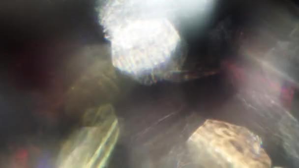 Голографическая смесь абстрактных объектов, боке плавающих в темноте . — стоковое видео